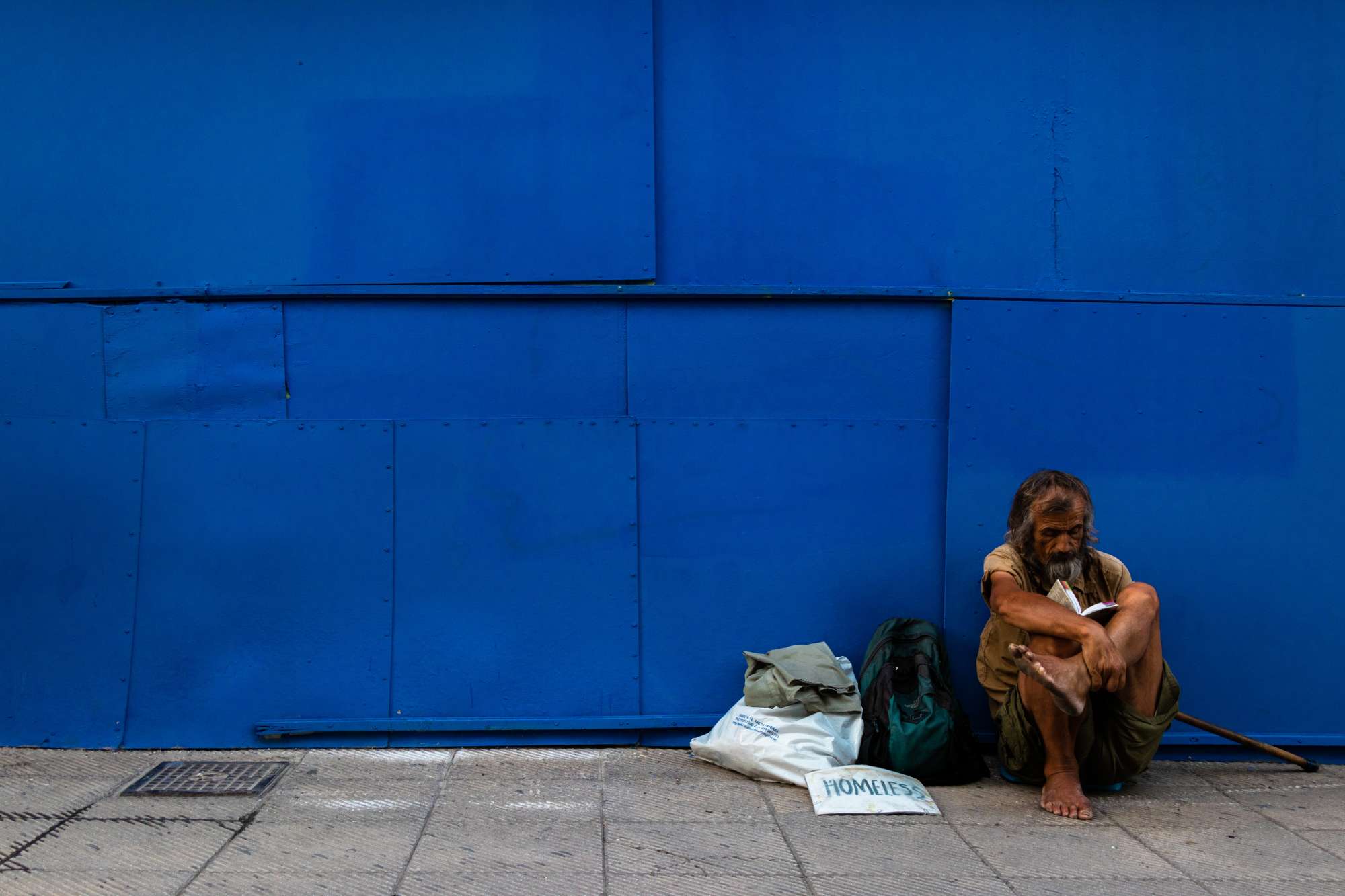 Homeless man sitting on blue wall